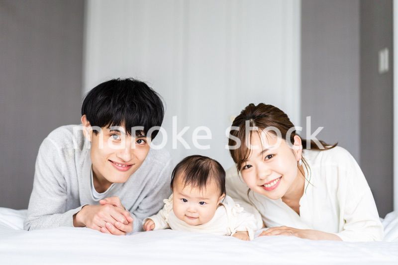 赤ちゃんと一緒に寝転ぶファミリー