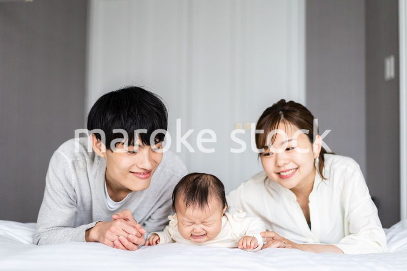 赤ちゃんと一緒に寝転ぶファミリー