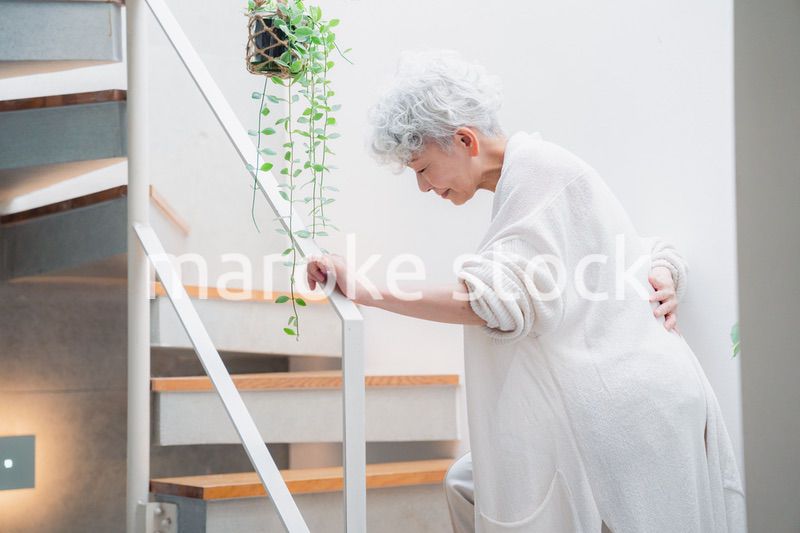 階段で腰痛に苦しむ高齢の女性