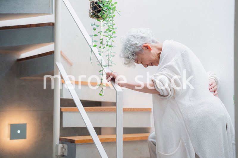 階段で腰痛に苦しむ高齢の女性