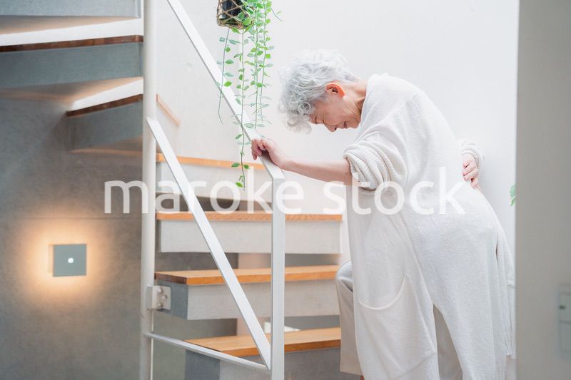階段で腰痛に苦しむ高齢の女性