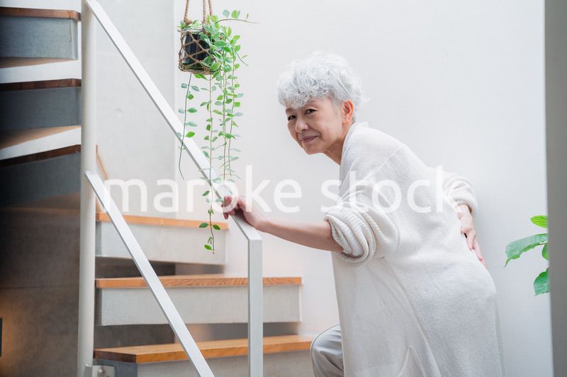階段で腰痛に苦しむ高齢の女性