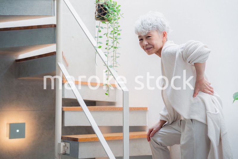 階段で腰痛に苦しむ高齢の女性
