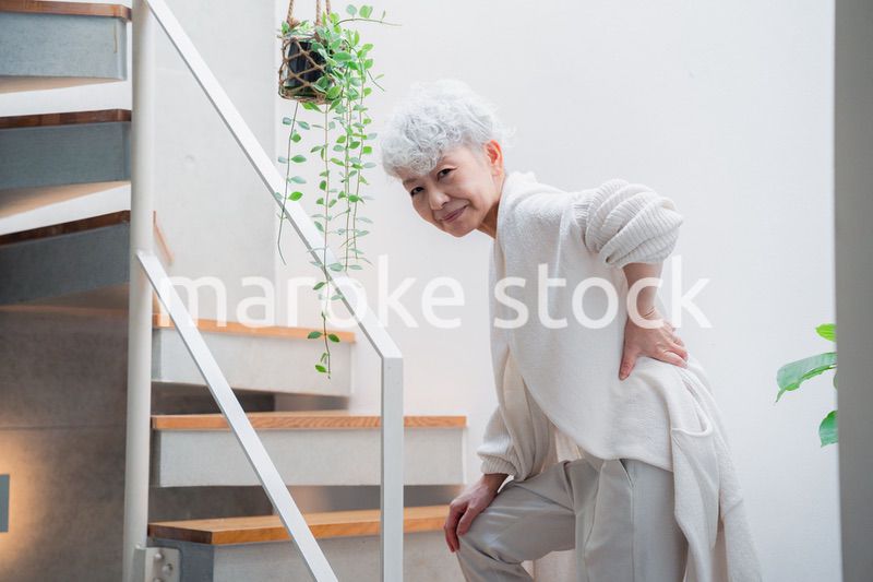 階段で腰痛に苦しむ高齢の女性