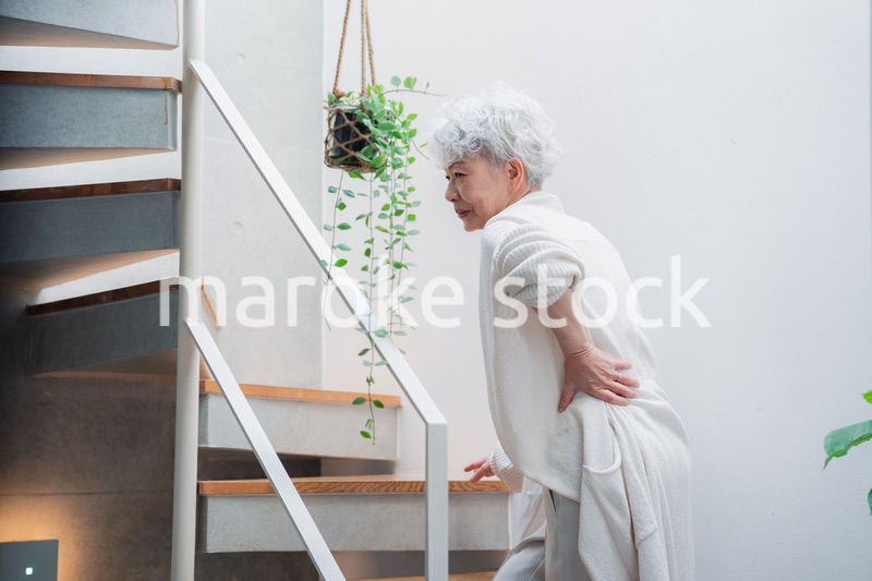 階段で腰痛に苦しむ高齢の女性