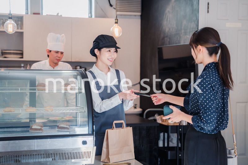 お菓子屋さんでクレジットカード決済をする女性