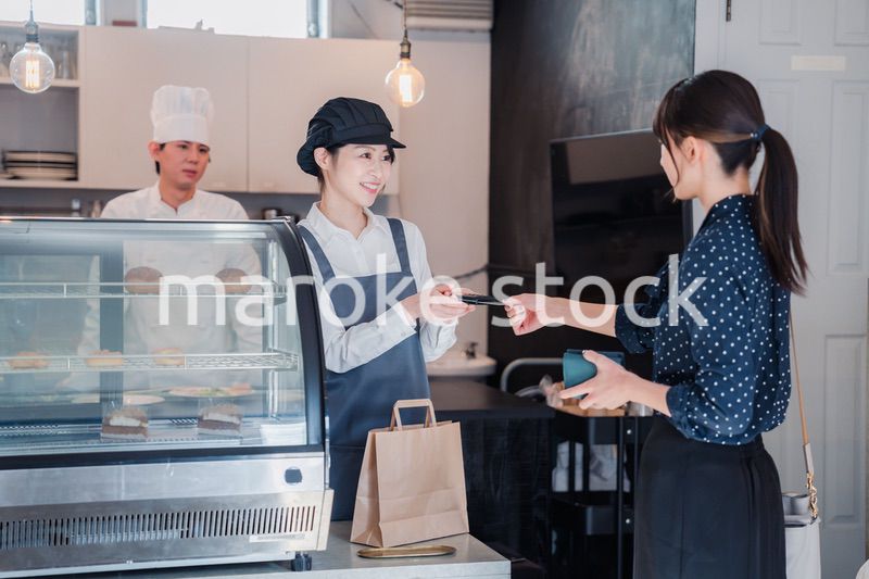 お菓子屋さんでクレジットカード決済をする女性