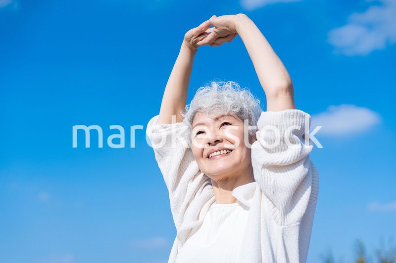 外で伸びをするシニアの女性