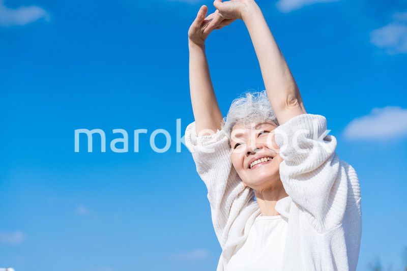 外で伸びをするシニアの女性