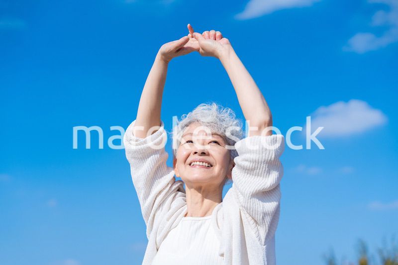 外で伸びをするシニアの女性