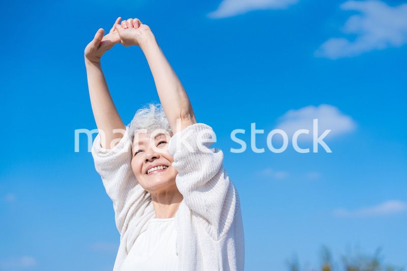 外で伸びをするシニアの女性