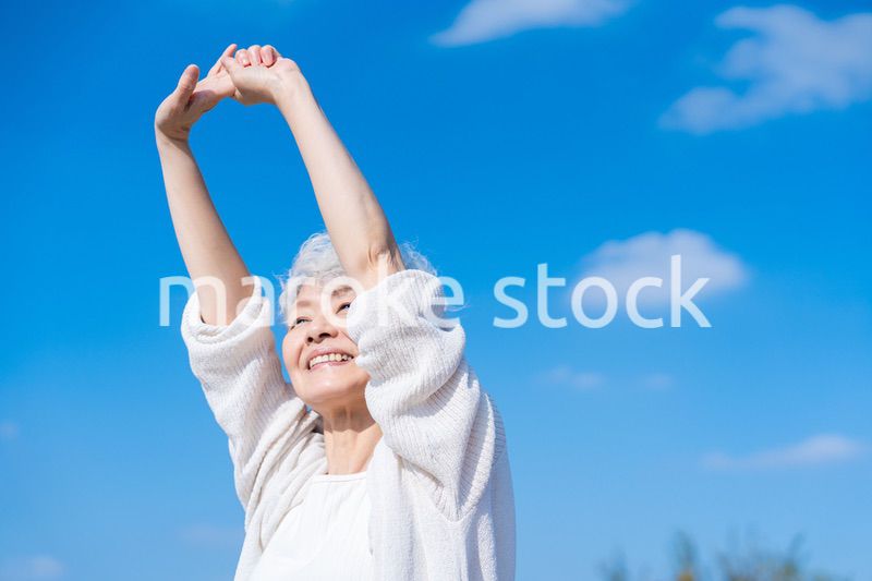 外で伸びをするシニアの女性
