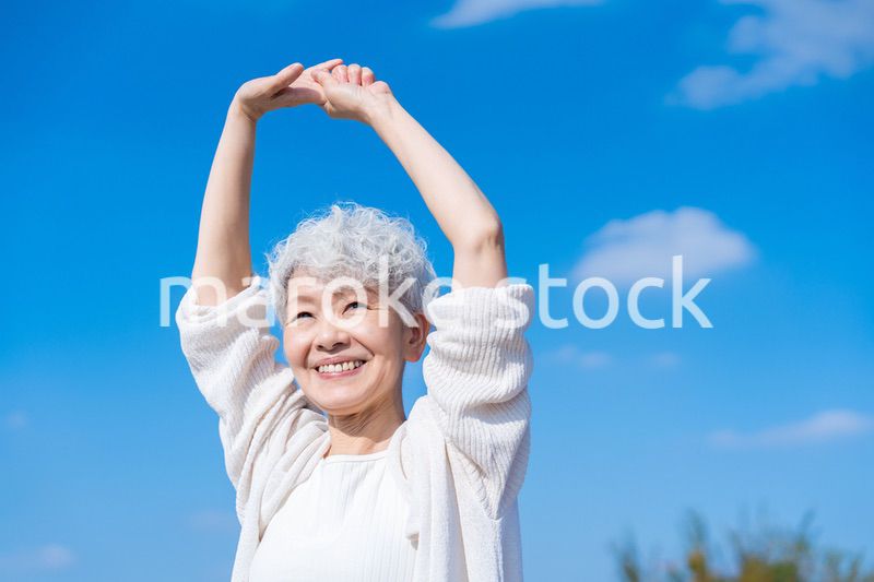 外で伸びをするシニアの女性