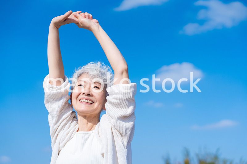 外で伸びをするシニアの女性