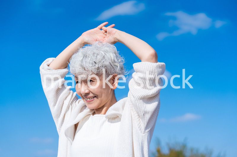 外で伸びをするシニアの女性