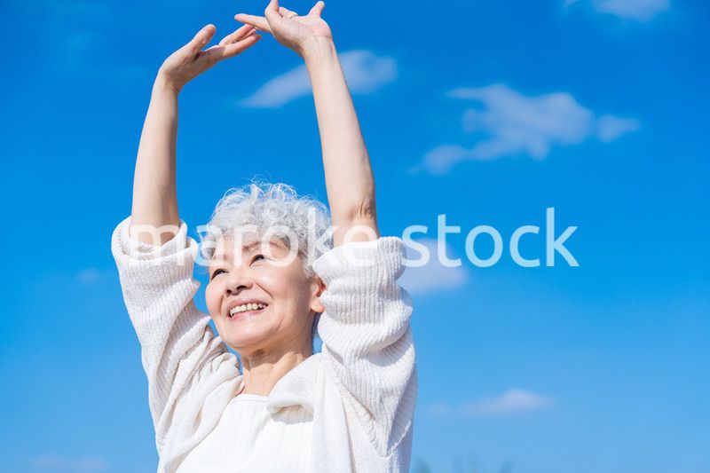 外で伸びをするシニアの女性