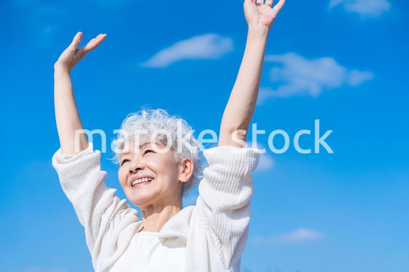 外で伸びをするシニアの女性