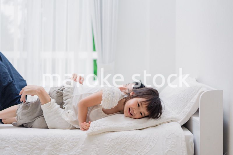パパと一緒にベッドで遊ぶ小さな女の子