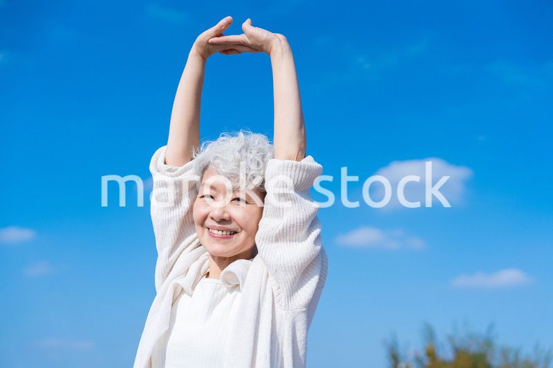 外で伸びをするシニアの女性