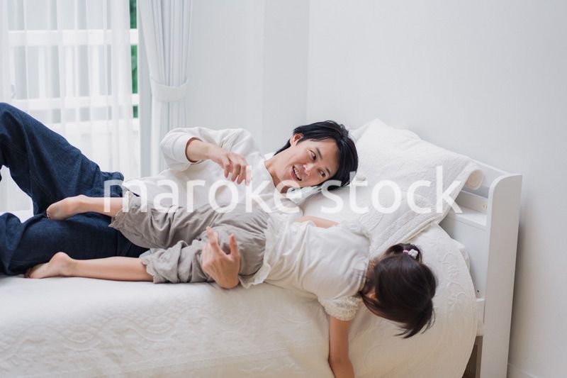 パパと一緒にベッドで遊ぶ小さな女の子