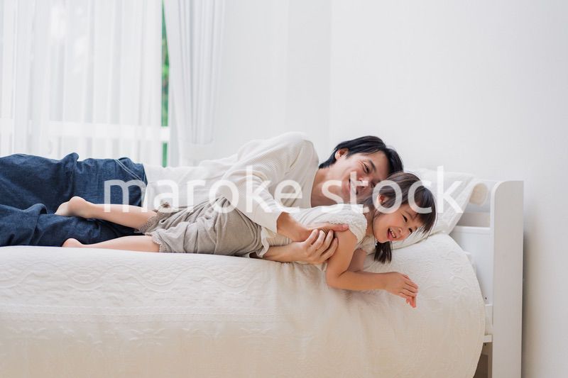 パパと一緒にベッドで遊ぶ小さな女の子