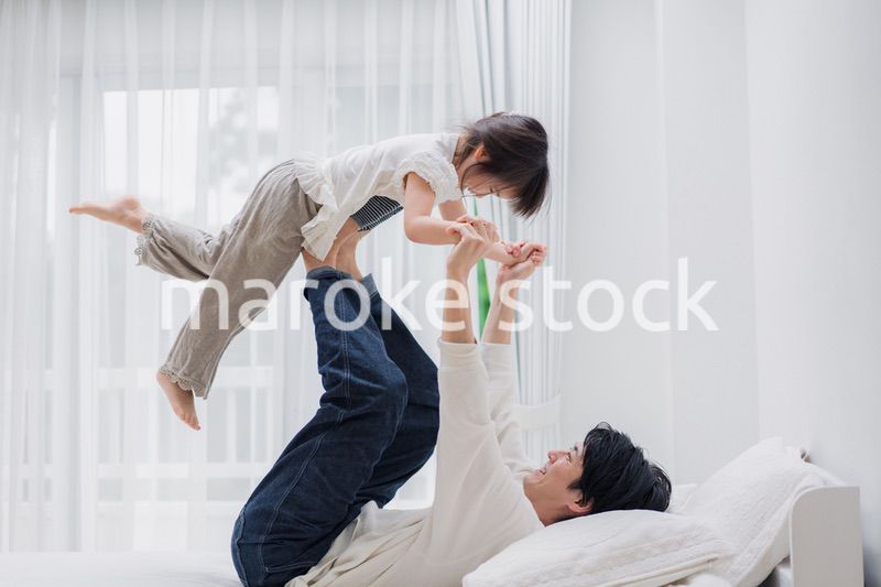 パパと一緒にベッドで遊ぶ小さな女の子