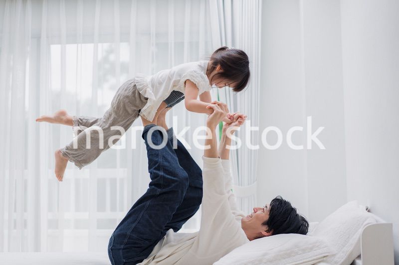 パパと一緒にベッドで遊ぶ小さな女の子