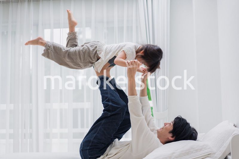 パパと一緒にベッドで遊ぶ小さな女の子