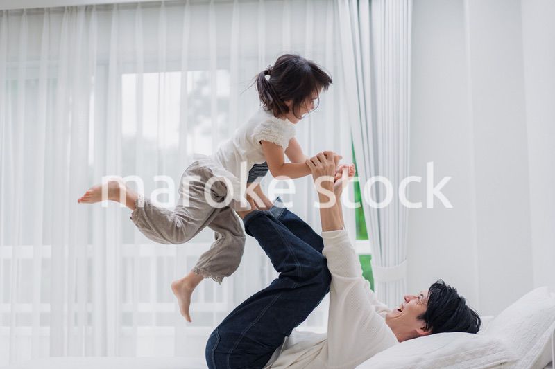 パパと一緒にベッドで遊ぶ小さな女の子