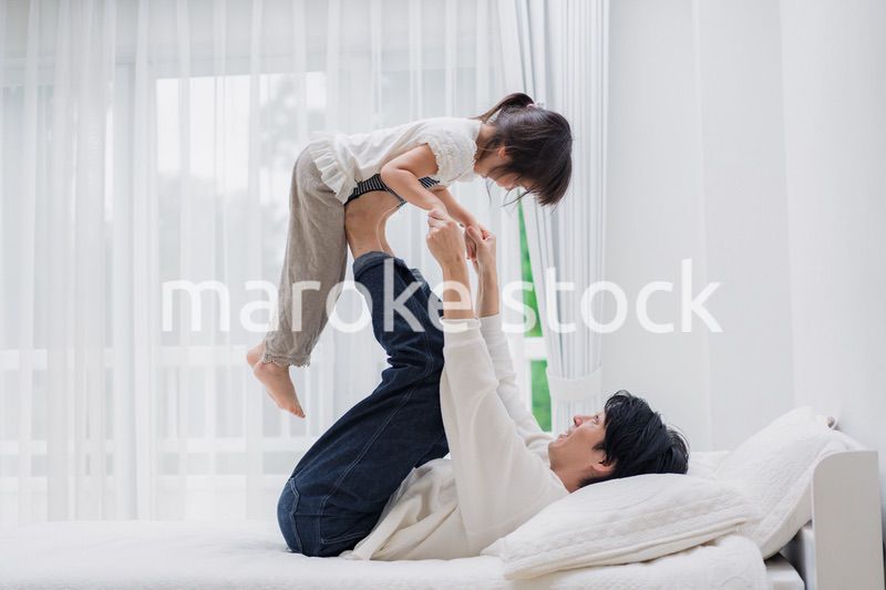 パパと一緒にベッドで遊ぶ小さな女の子