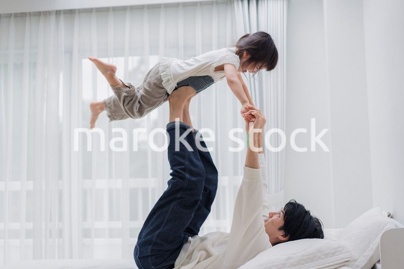 パパと一緒にベッドで遊ぶ小さな女の子