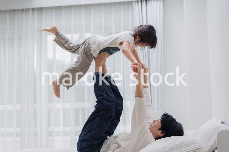 パパと一緒にベッドで遊ぶ小さな女の子