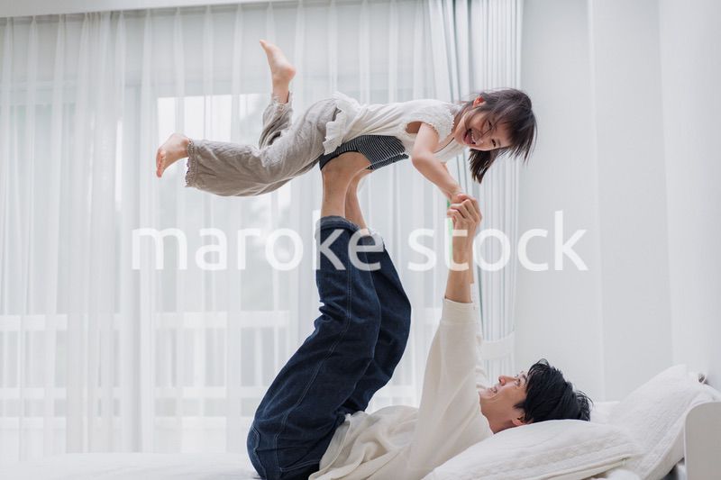 パパと一緒にベッドで遊ぶ小さな女の子