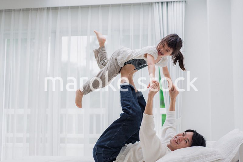 パパと一緒にベッドで遊ぶ小さな女の子