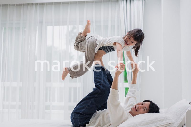 パパと一緒にベッドで遊ぶ小さな女の子