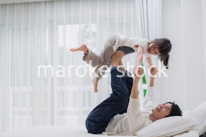 パパと一緒にベッドで遊ぶ小さな女の子