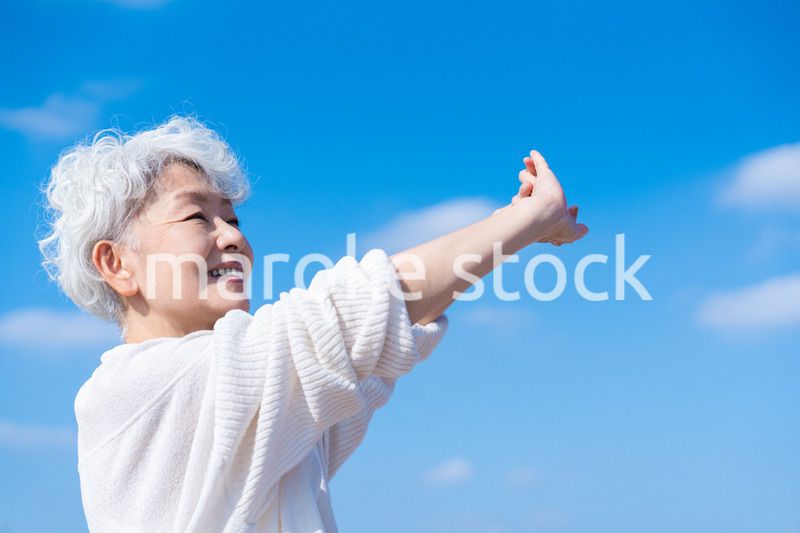 外で伸びをするシニアの女性