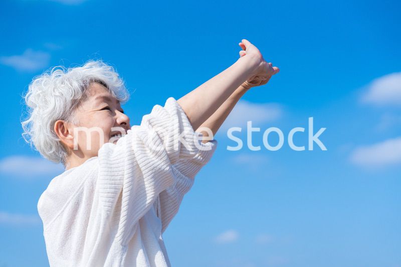 外で伸びをするシニアの女性