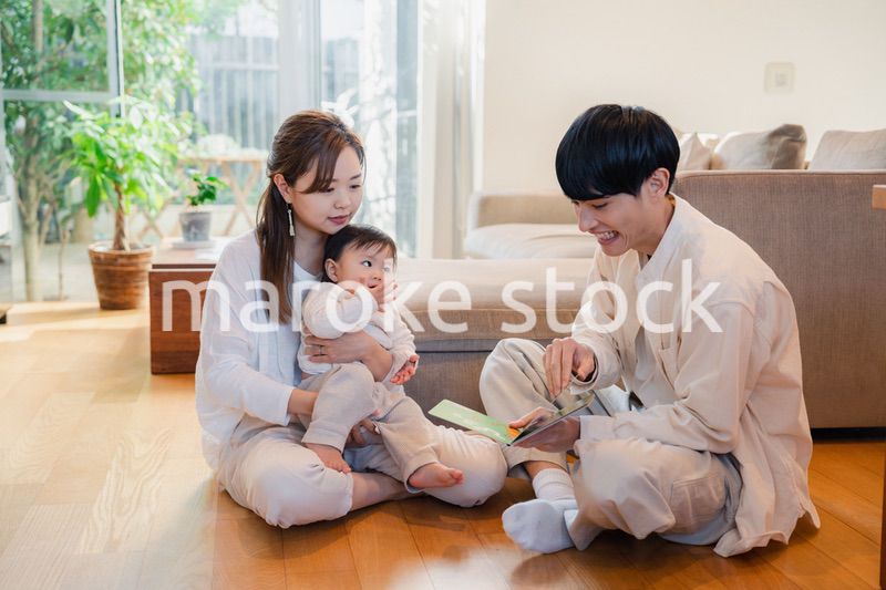 赤ちゃんに絵本の読み聞かせをする両親