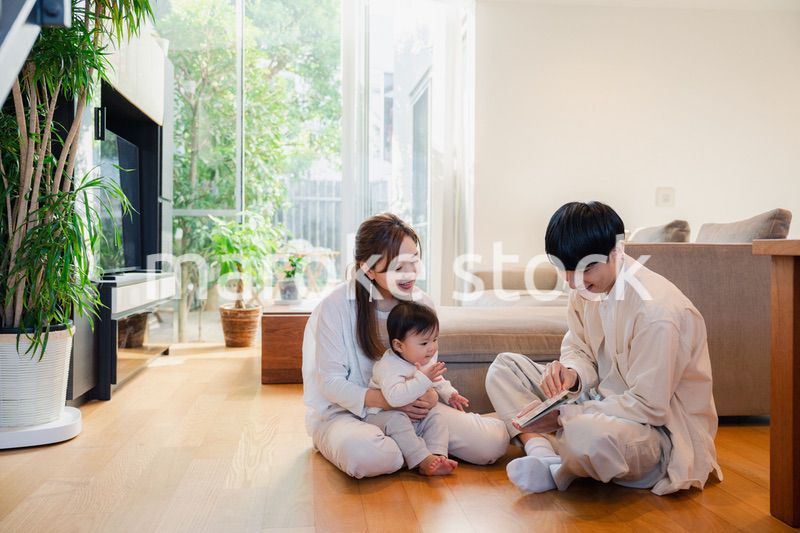 赤ちゃんに絵本の読み聞かせをする両親