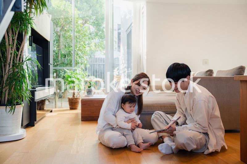 赤ちゃんに絵本の読み聞かせをする両親