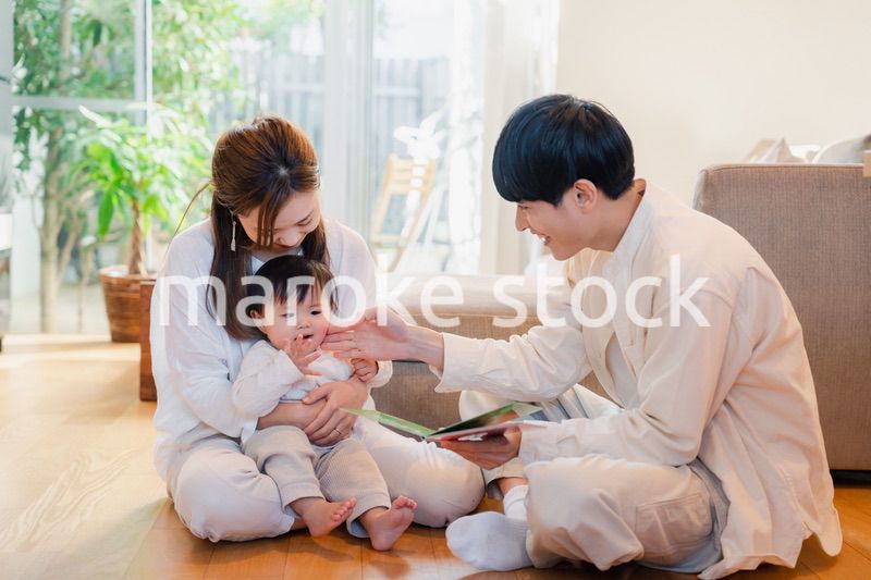 赤ちゃんに絵本の読み聞かせをする両親