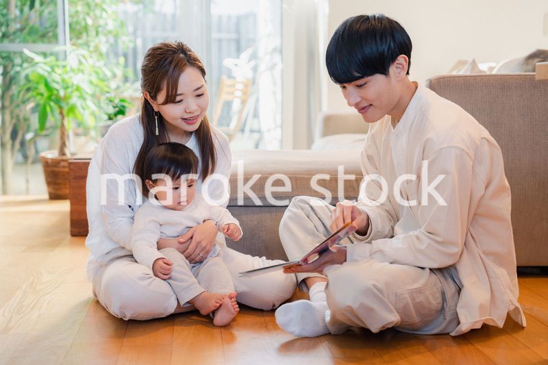 赤ちゃんに絵本の読み聞かせをする両親