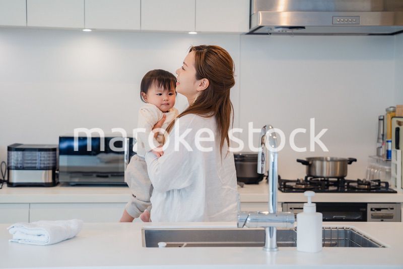 赤ちゃんを抱っこしながら家事をするお母さん