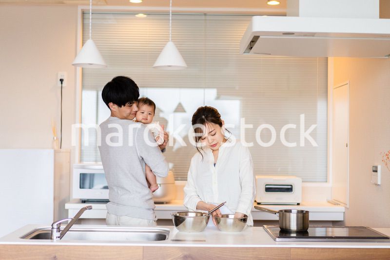 キッチンで料理をするお母さんとお父さんと赤ちゃん