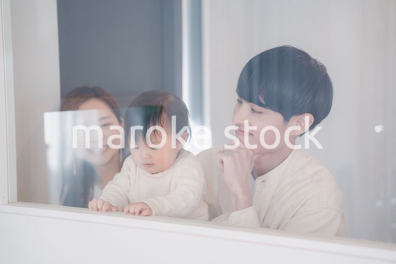 窓から外を見る赤ちゃんと両親