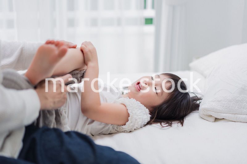 パパと一緒にベッドで遊ぶ小さな女の子
