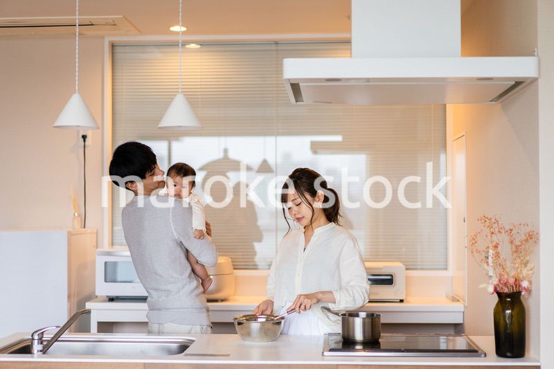 キッチンで料理をするお母さんとお父さんと赤ちゃん