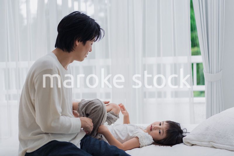 パパと一緒にベッドで遊ぶ小さな女の子