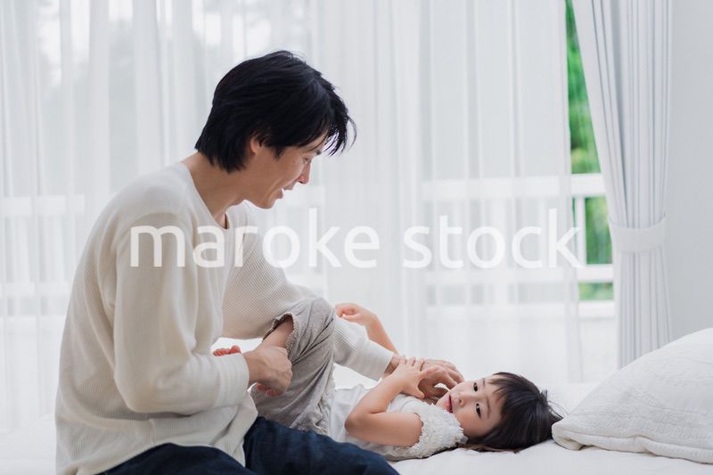 パパと一緒にベッドで遊ぶ小さな女の子